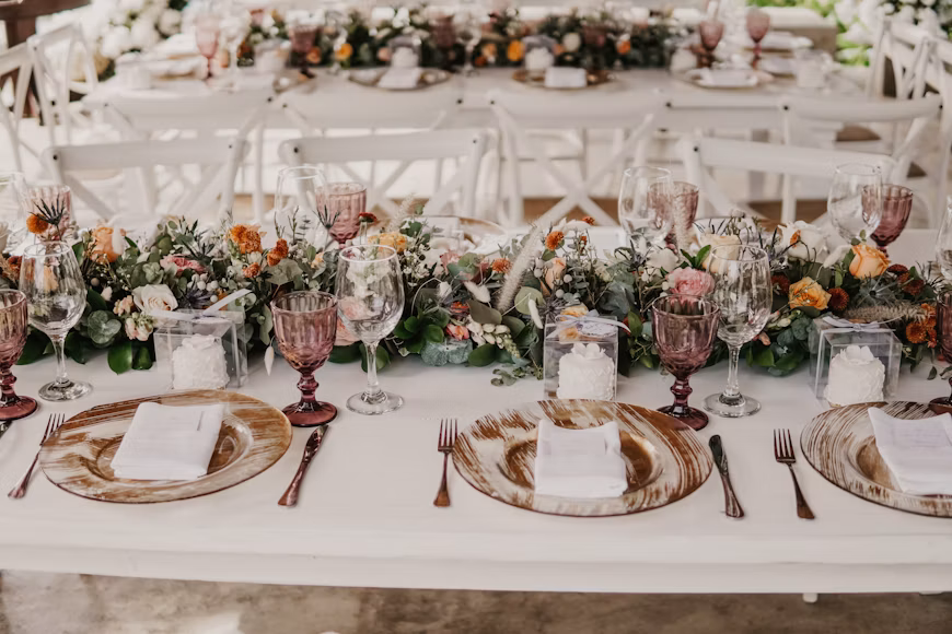 A tasting table laid with Rajasthani dishes in brass and copper serveware on an olive linen runner, hands plating in the background